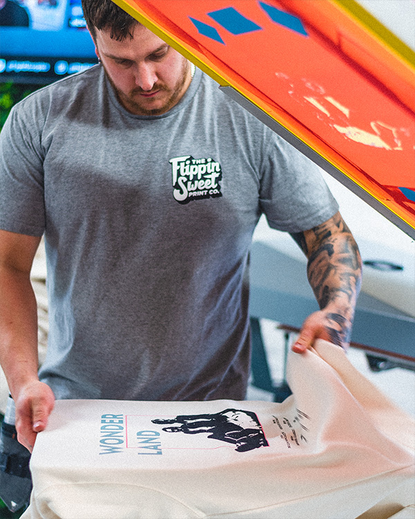 Screen printer holding a custom printed band hoodie in a print studio