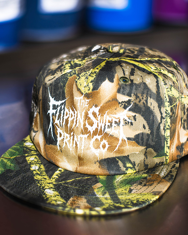 Screen printed camouflage cap with custom white artwork